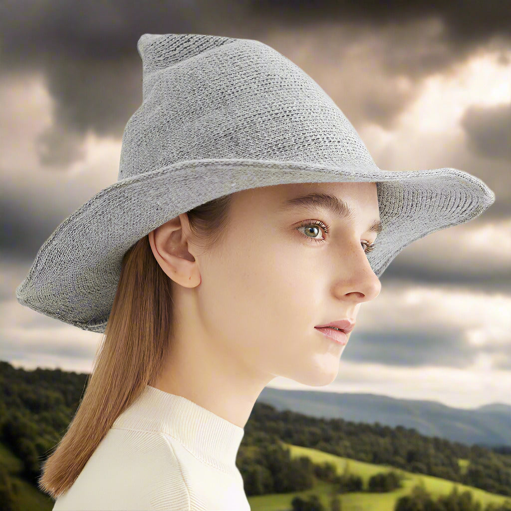 Woman wearing a gray wide-brimmed hat on a light background